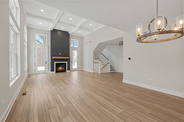 unfurnished living room with light wood-style floors, coffered ceiling, beamed ceiling, baseboards, and stairs