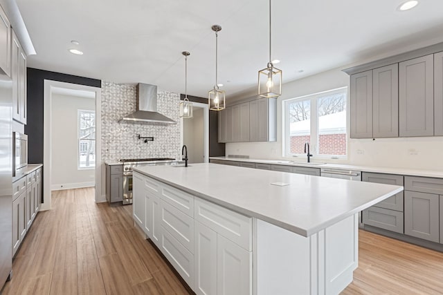 kitchen featuring wall chimney range hood, appliances with stainless steel finishes, and gray cabinetry