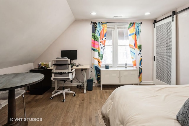 bedroom featuring a barn door, recessed lighting, wood finished floors, visible vents, and vaulted ceiling