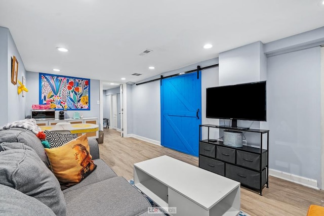 living room featuring light wood-type flooring, baseboards, recessed lighting, and a barn door