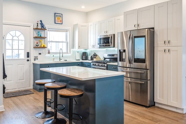 kitchen with a center island, a breakfast bar area, stainless steel appliances, light countertops, and a sink