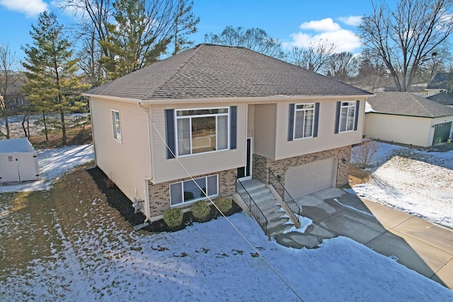 view of front of property with driveway, roof with shingles, a garage, and brick siding