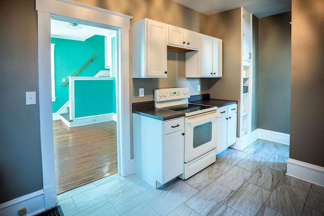 kitchen with marble finish floor, white electric range oven, dark countertops, white cabinets, and baseboards