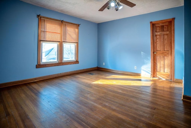 spare room featuring visible vents, baseboards, a ceiling fan, dark wood-style floors, and a textured ceiling