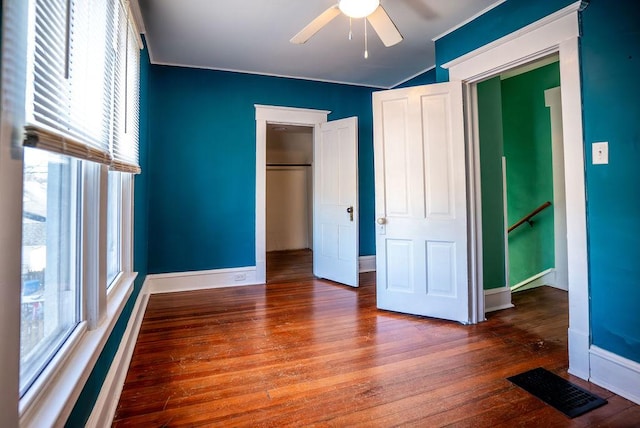 unfurnished bedroom with wood finished floors, a ceiling fan, visible vents, baseboards, and a closet