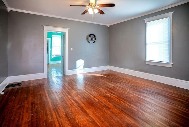 unfurnished room featuring baseboards, wood finished floors, visible vents, and crown molding