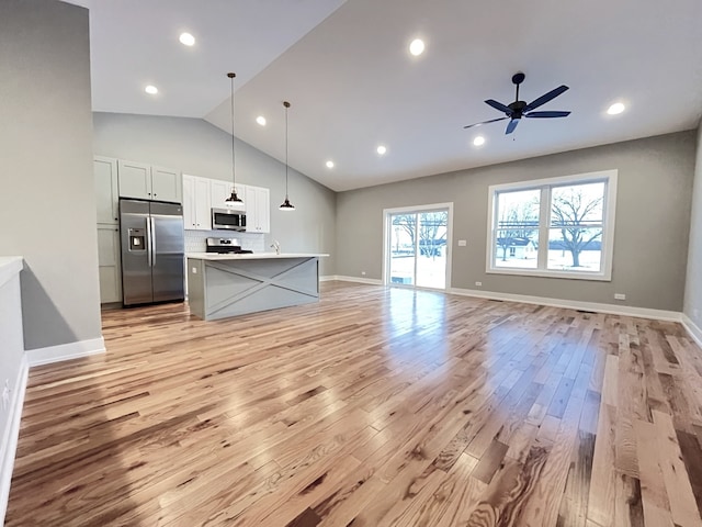 kitchen with decorative light fixtures, light countertops, appliances with stainless steel finishes, open floor plan, and white cabinetry