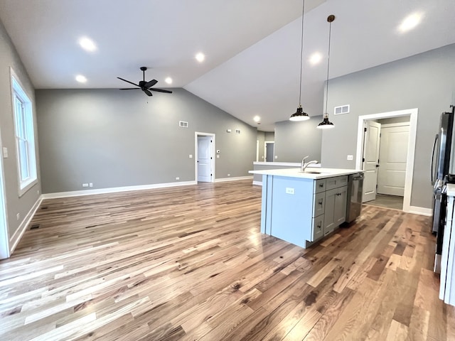 kitchen with a center island with sink, visible vents, decorative light fixtures, light countertops, and a sink