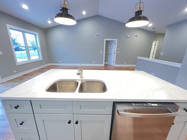 kitchen featuring an island with sink, light stone countertops, a sink, and dishwasher