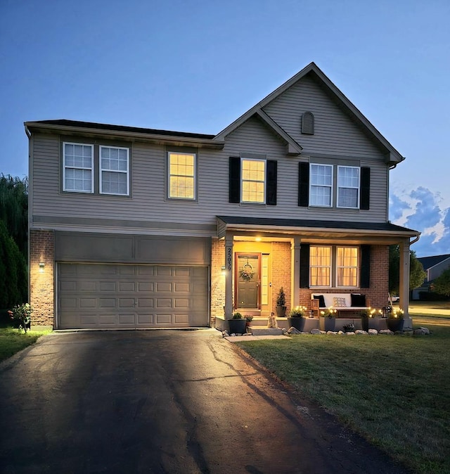 traditional home with an attached garage, covered porch, aphalt driveway, and brick siding