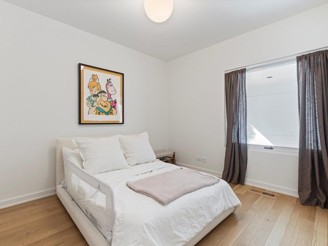 bedroom with light wood-type flooring, visible vents, and baseboards