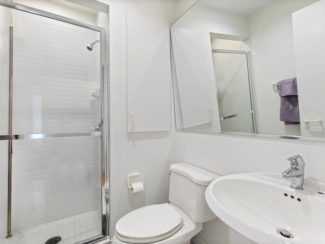 bathroom featuring a shower stall, toilet, and a sink