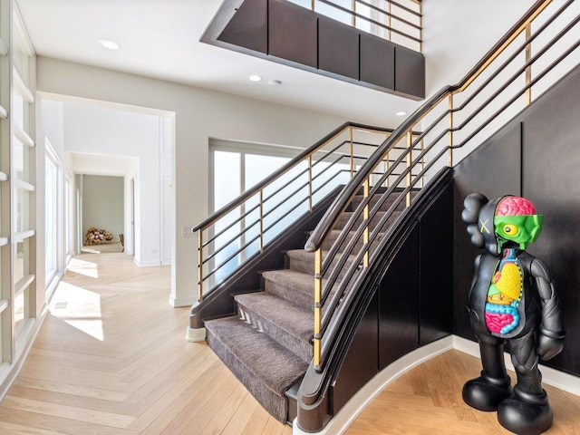 stairway with parquet flooring, recessed lighting, baseboards, and a towering ceiling