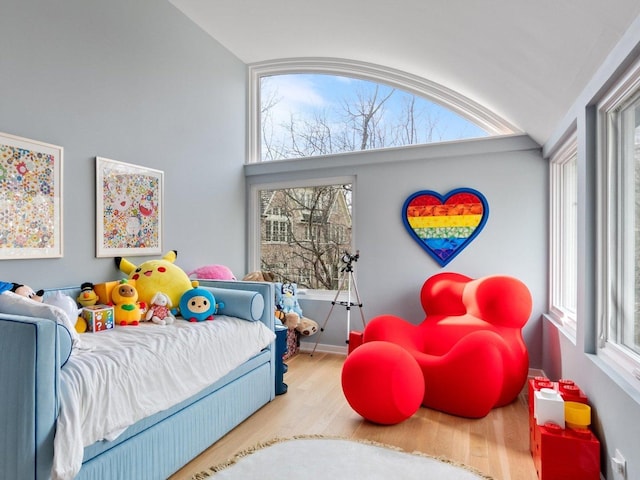 bedroom with vaulted ceiling, baseboards, and wood finished floors