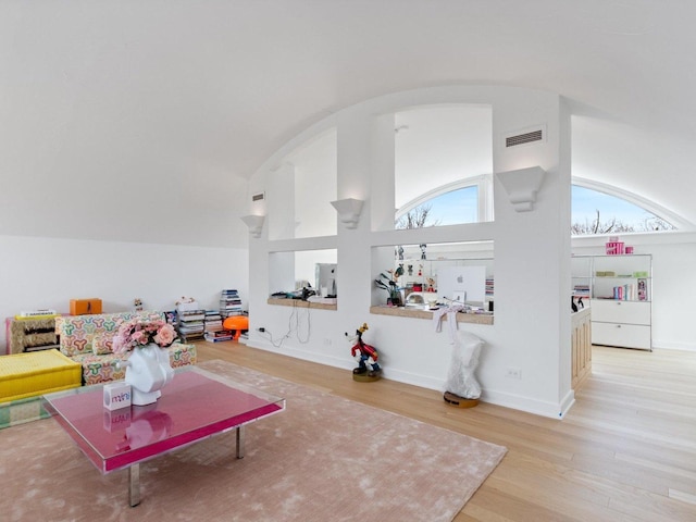 living area featuring high vaulted ceiling, wood finished floors, visible vents, and baseboards