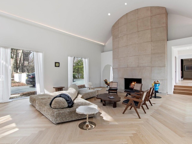 living room with high vaulted ceiling and a tiled fireplace