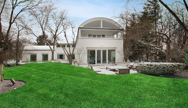 back of property with stucco siding, a patio, a lawn, and a balcony