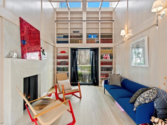 living area with a wealth of natural light, a towering ceiling, wood finished floors, and a fireplace