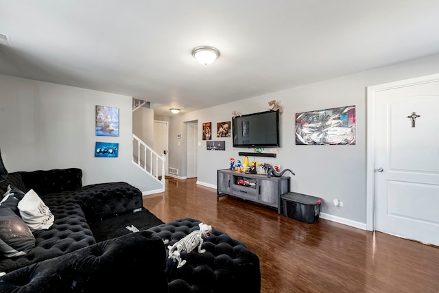 living room with visible vents, baseboards, wood finished floors, and stairs