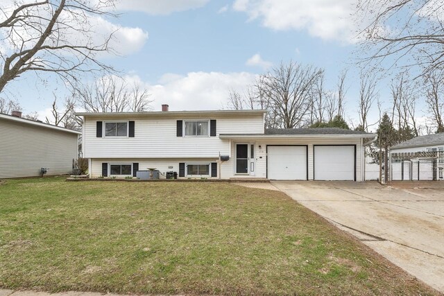 split level home with central AC, a front yard, an attached garage, a chimney, and concrete driveway
