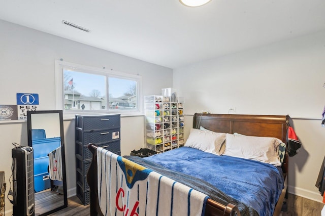 bedroom featuring wood finished floors, baseboards, and visible vents