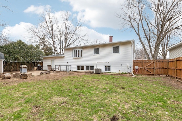 rear view of house with a fenced backyard, a lawn, a gate, a chimney, and central AC unit
