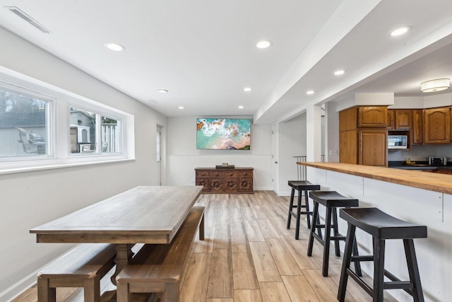 dining room featuring light wood-style floors, baseboards, visible vents, and recessed lighting