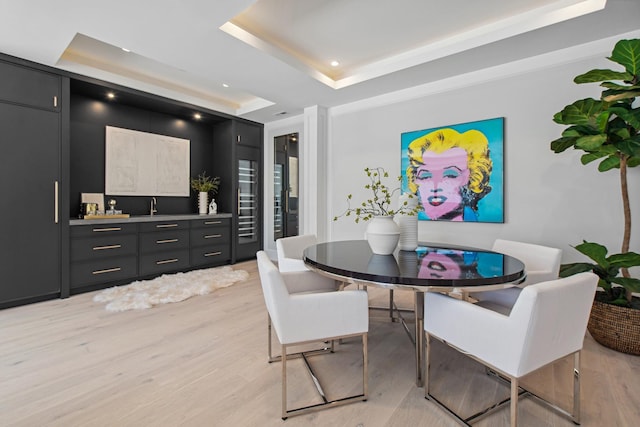 dining space with light wood finished floors, a tray ceiling, and recessed lighting