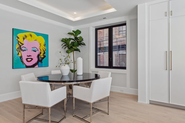 dining room with recessed lighting, visible vents, baseboards, light wood-style floors, and a raised ceiling