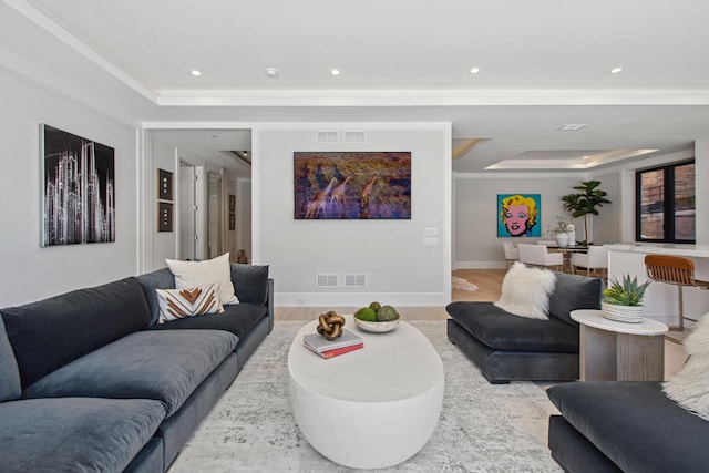 living room with a tray ceiling, visible vents, and light wood-style floors