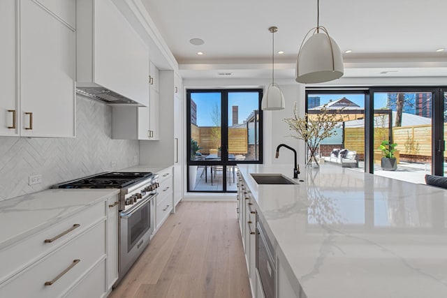 kitchen featuring high end stainless steel range, a sink, decorative light fixtures, and light stone countertops