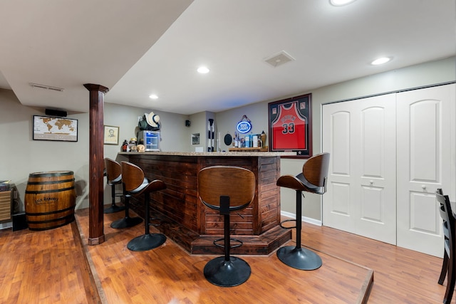 bar with a dry bar, visible vents, wood finished floors, and recessed lighting