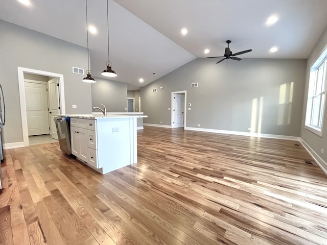 kitchen featuring open floor plan, decorative light fixtures, a center island with sink, and white cabinetry