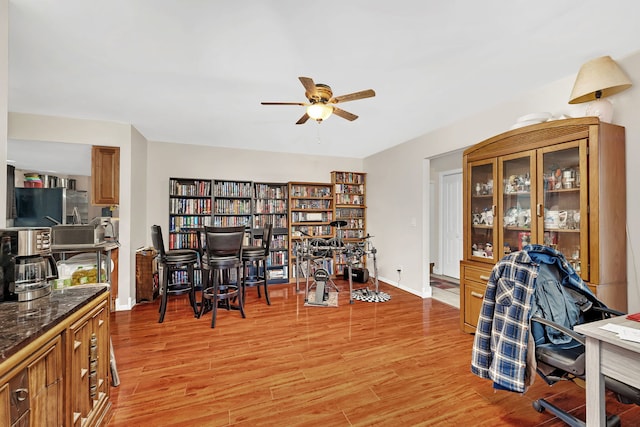 office space with a ceiling fan, light wood-type flooring, and baseboards