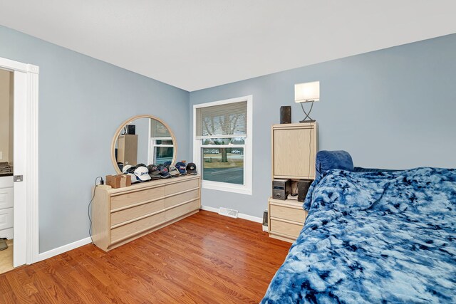 bedroom with light wood-type flooring, visible vents, and baseboards