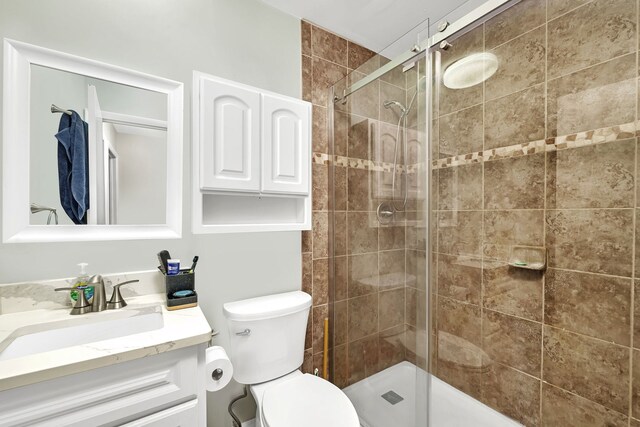 bathroom with a stall shower, vanity, and toilet