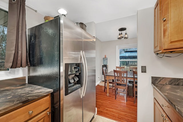 kitchen featuring brown cabinets, dark countertops, stainless steel fridge, and light wood-style flooring