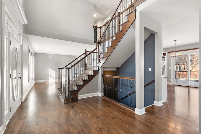 interior space featuring a towering ceiling, baseboards, a chandelier, and dark wood-style flooring