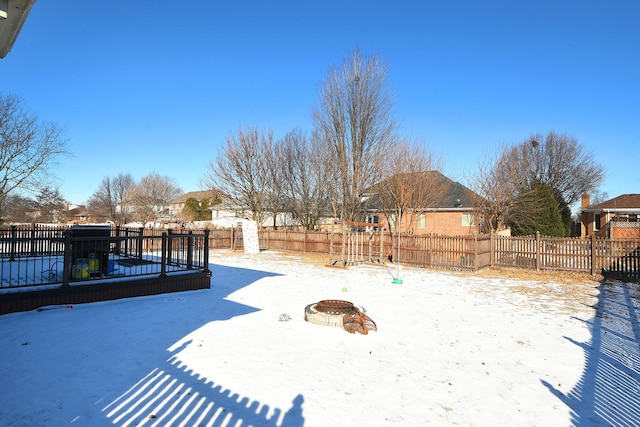 snowy yard featuring an outdoor fire pit and a fenced backyard