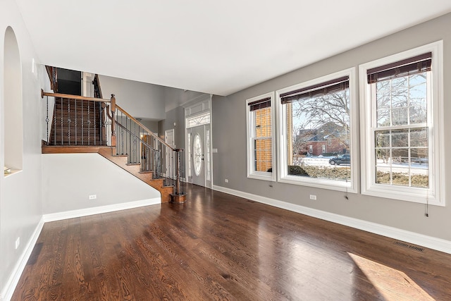 entryway with arched walkways, wood finished floors, visible vents, baseboards, and stairway