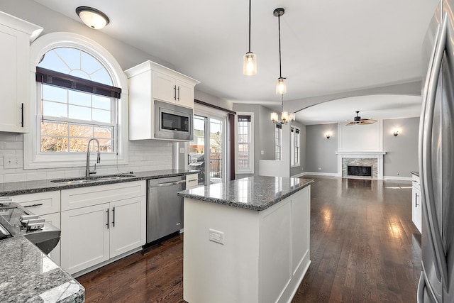 kitchen with appliances with stainless steel finishes, dark stone counters, white cabinets, and a sink