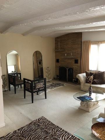 living room featuring arched walkways, carpet floors, beamed ceiling, and a brick fireplace