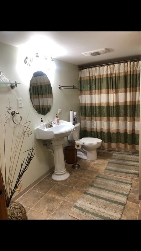 bathroom with toilet, a shower with shower curtain, and tile patterned floors