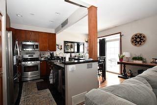 kitchen featuring dark countertops, open floor plan, a peninsula, stainless steel appliances, and ornate columns