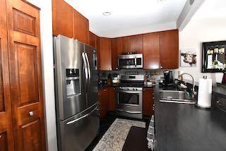 kitchen with dark countertops, appliances with stainless steel finishes, brown cabinets, and a sink