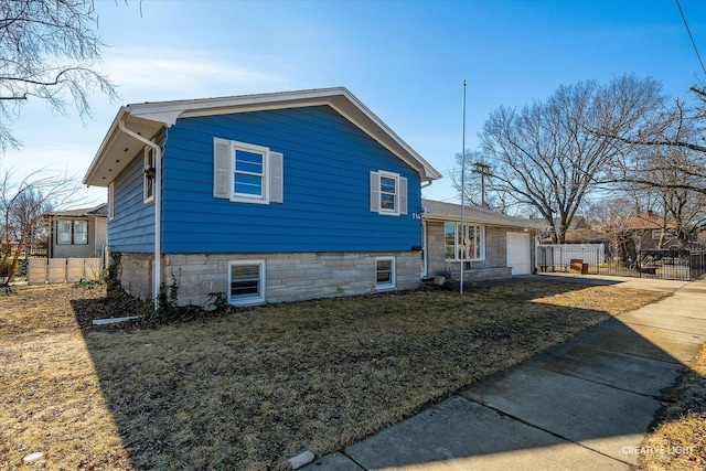 view of home's exterior with an attached garage, driveway, and fence