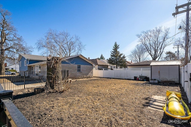 view of yard featuring a storage unit, an outbuilding, and a fenced backyard