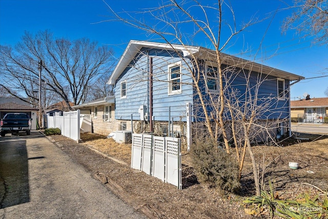 view of side of property featuring driveway, a garage, and fence