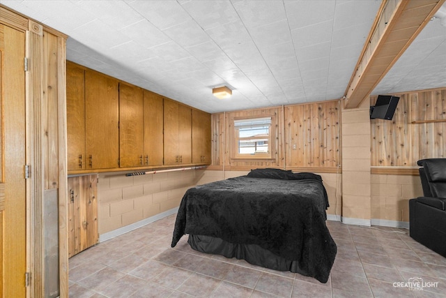 bedroom with light tile patterned flooring and wood walls