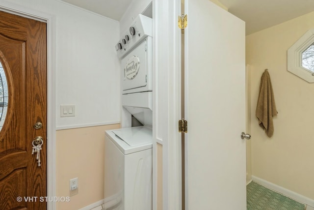 washroom with stacked washer and clothes dryer, baseboards, and laundry area